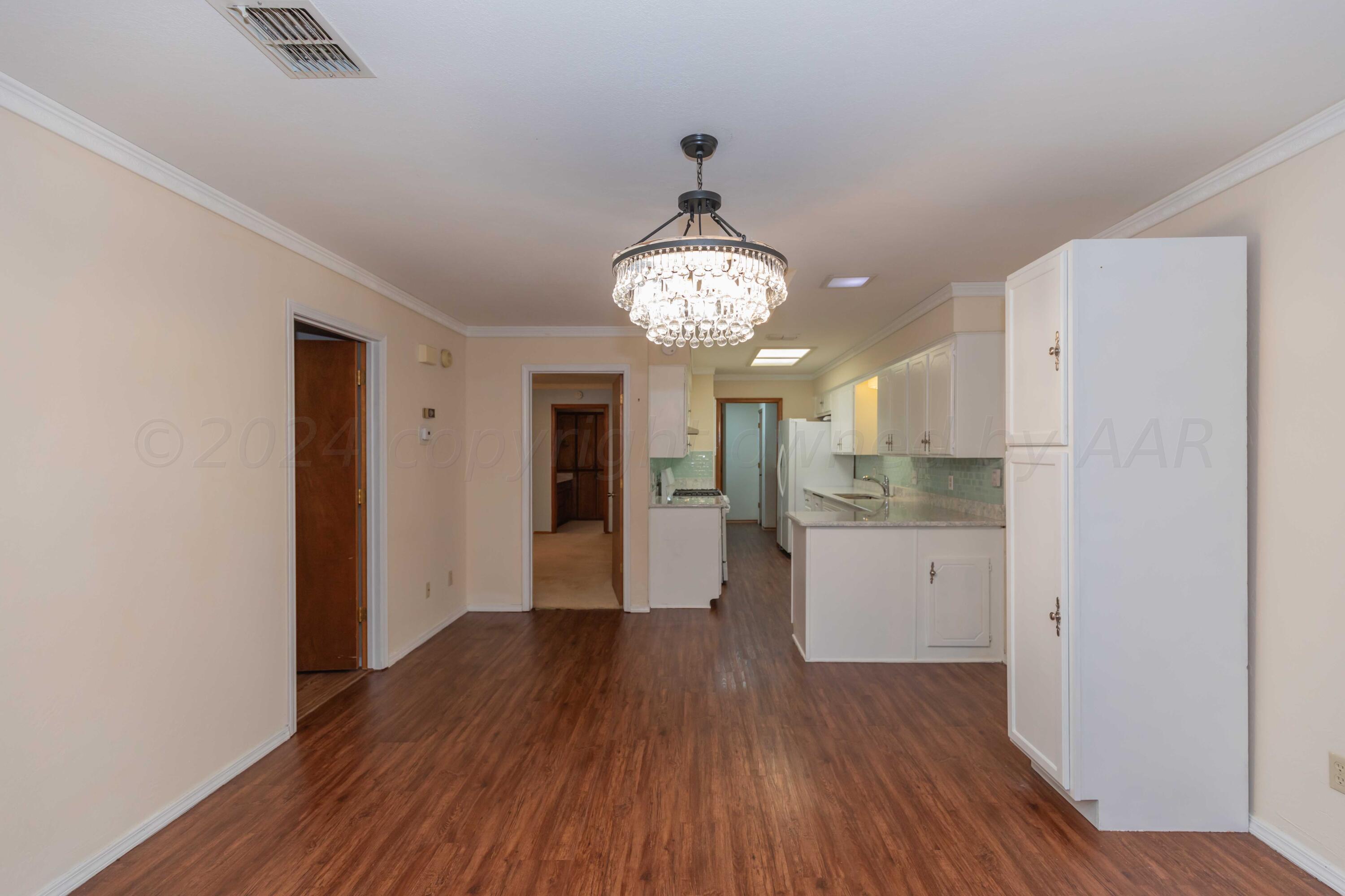 3406 Gladstone Lane Amarillo, TX 79121 - Photo 13 of 35 a view of a hallway with wooden floor and a kitchen