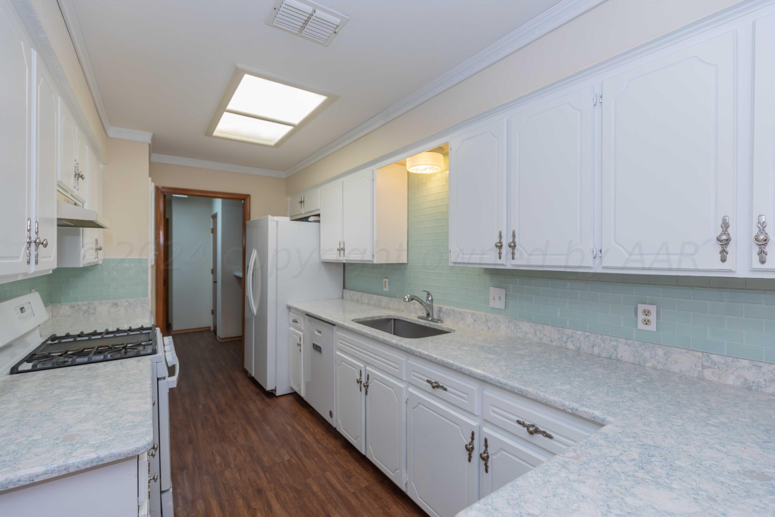 3406 Gladstone Lane Amarillo, TX 79121 - Photo 8 of 35 a kitchen that has a lot of cabinets in it and wooden floors