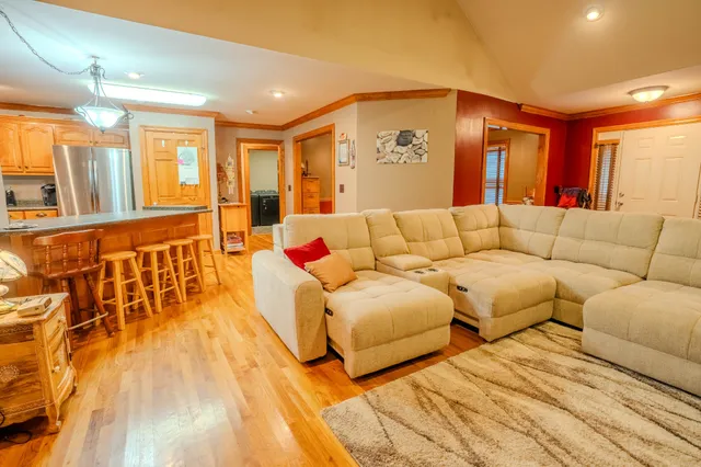 a kitchen with stainless steel appliances granite countertop a refrigerator a sink dishwasher a stove and a dining table with wooden floor