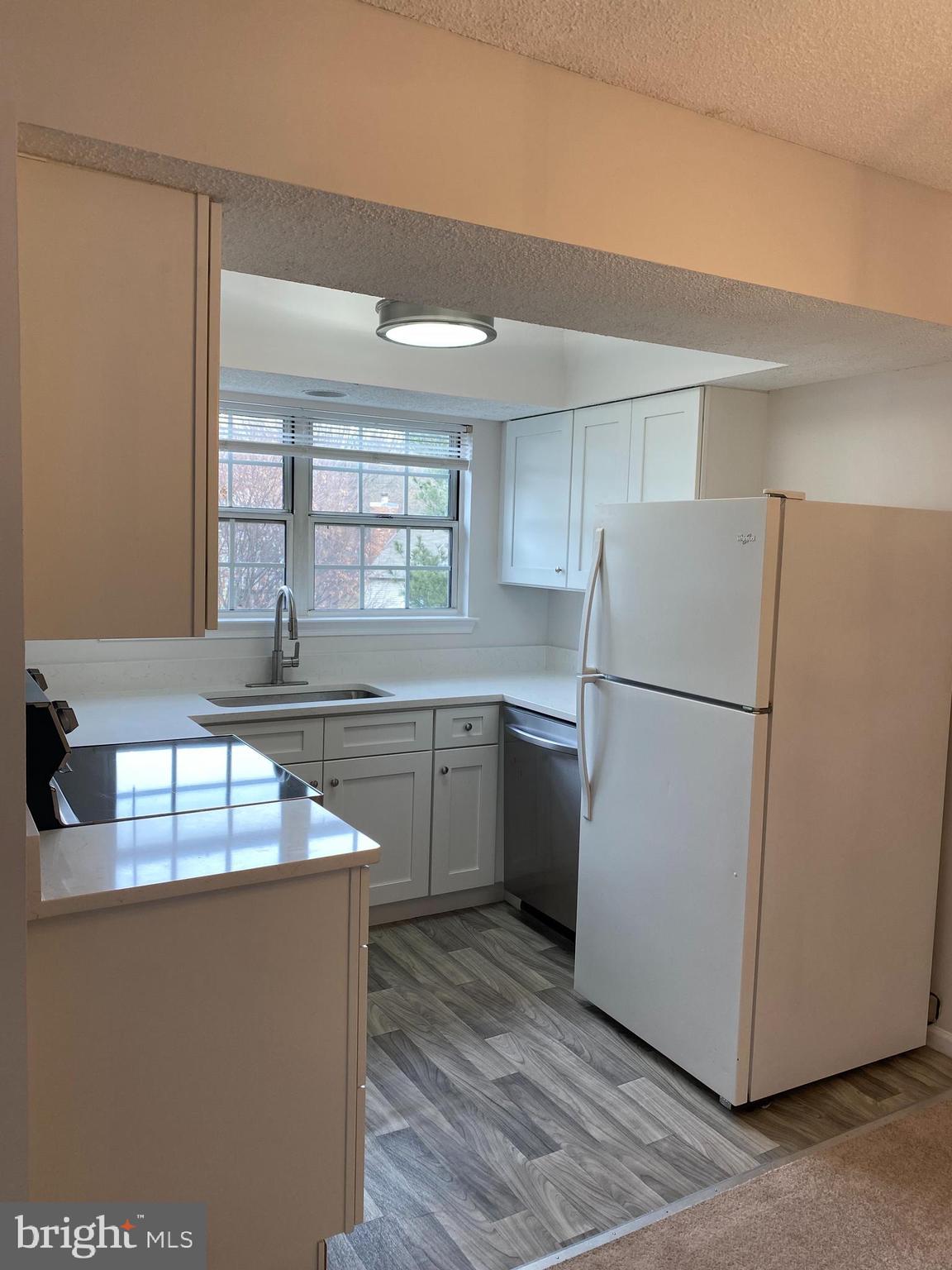 12106 Greenway Court, Unit 302 Fairfax, VA 22033 - Photo 5 of 20 a kitchen with kitchen island a counter top space a sink and a refrigerator