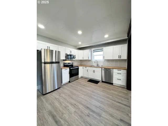 a large kitchen with stainless steel appliances granite countertop a refrigerator and a stove top oven