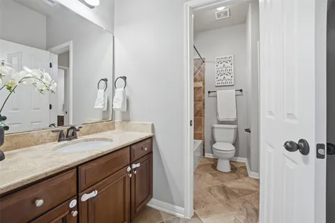 a bathroom with a granite countertop sink a mirror and a toilet
