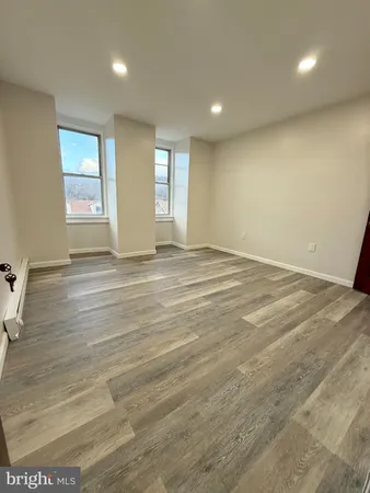 a view of an empty room with window and wooden floor