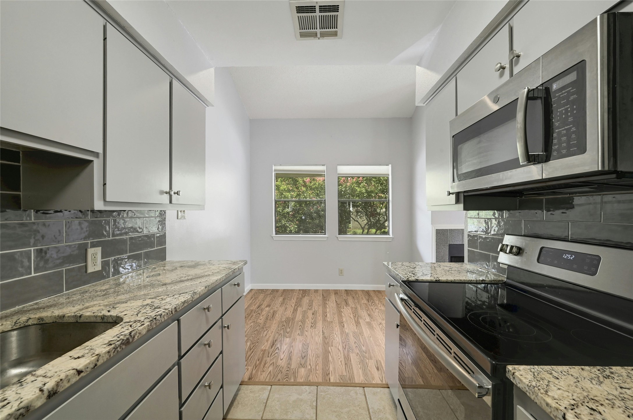 9226 Jollyville Road, Unit 221 Austin, TX 78759 - Photo 10 of 20 A galley kitchen with granite counters and contemporary stainless steel appliances awaits culinary endeavors.