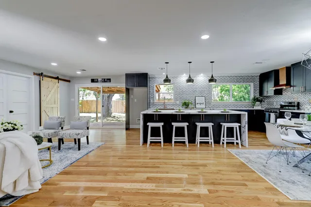 a kitchen with stainless steel appliances granite countertop a stove top oven a sink dishwasher and a dining table with wooden floor