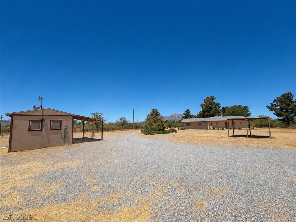 1611 West Blosser Ranch Road Pahrump, NV 89060 - Photo 24 of 25 Discover a tranquil retreat with a gravel driveway, mature trees, and a detached storage shed.