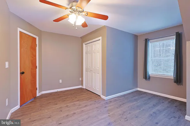 an empty room with chandelier fan and windows