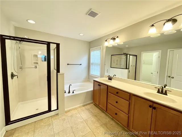 a spacious bathroom with a double vanity sink a mirror and a shower
