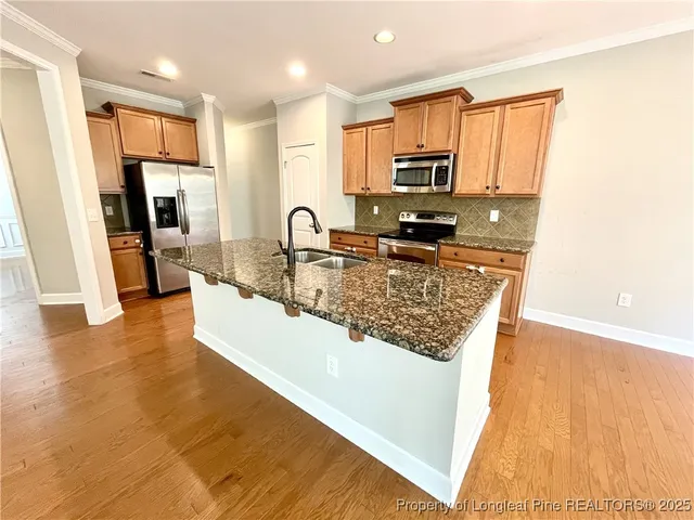 a view of a kitchen with kitchen island a sink wooden floor and counter top space