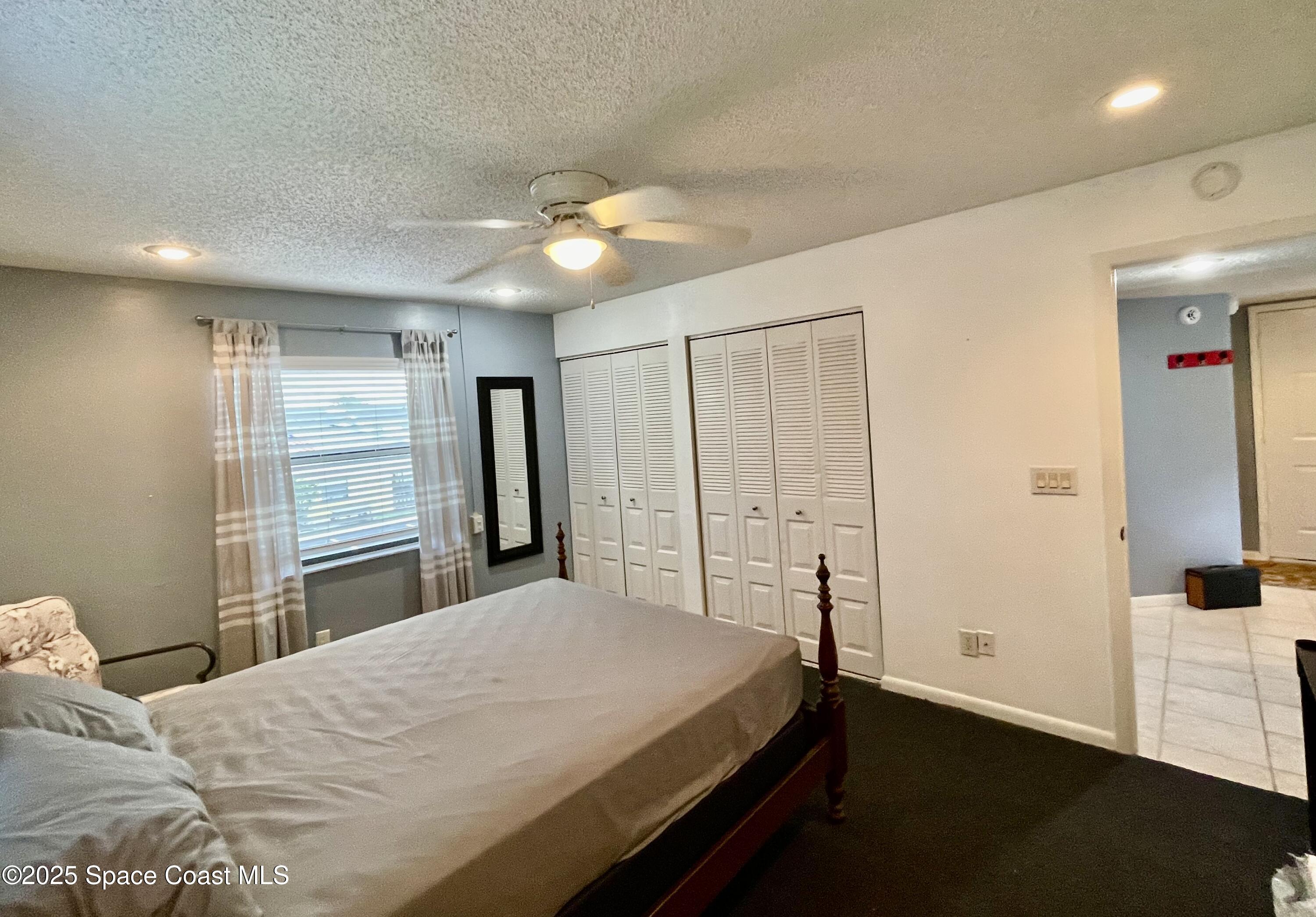 594 North Wickham Road, Unit 2 Melbourne, FL 32935 - Photo 16 of 42 a bedroom with a bed and a chandelier