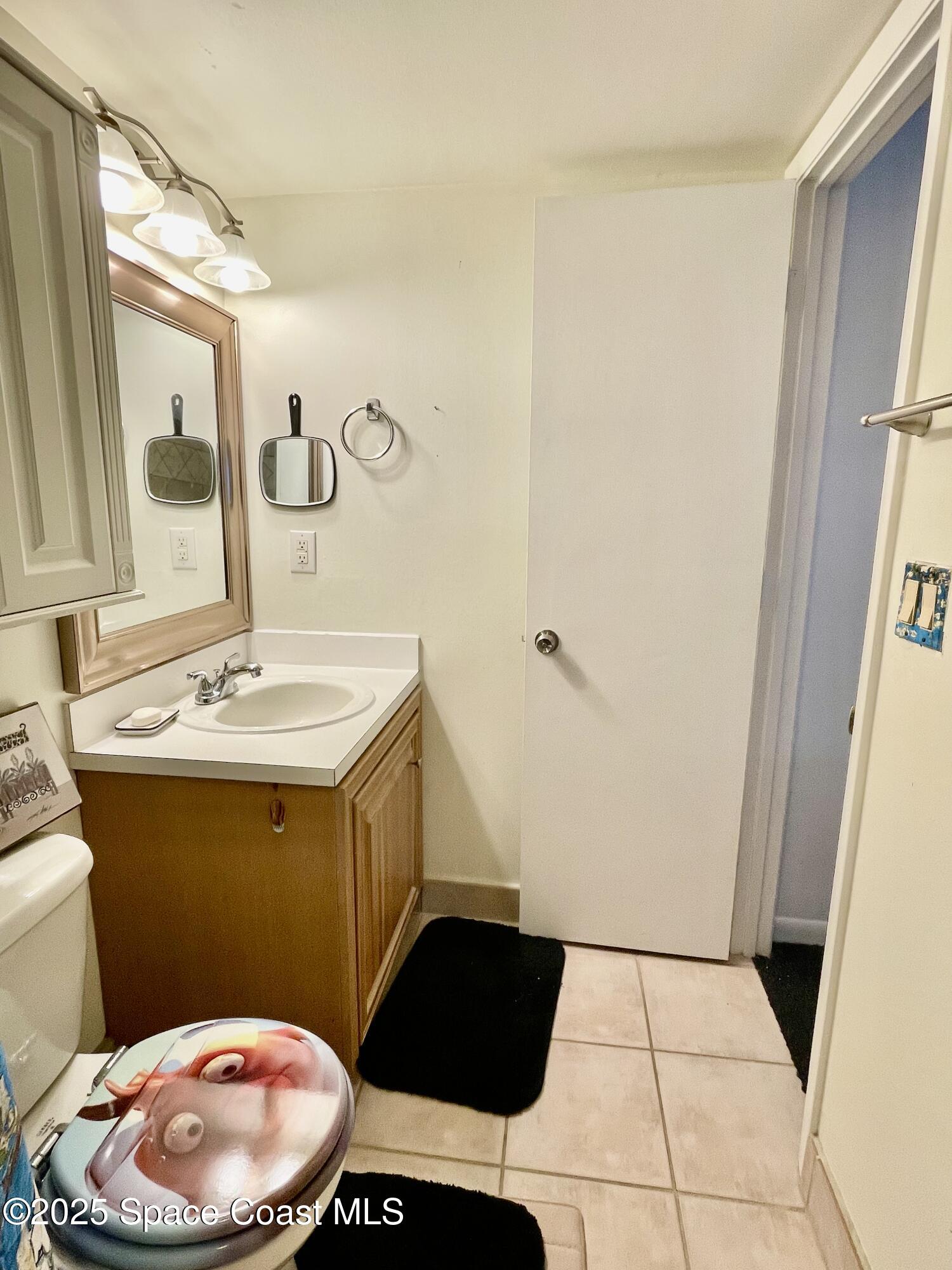 594 North Wickham Road, Unit 2 Melbourne, FL 32935 - Photo 20 of 42 a bathroom with a sink a toilet a mirror and vanity