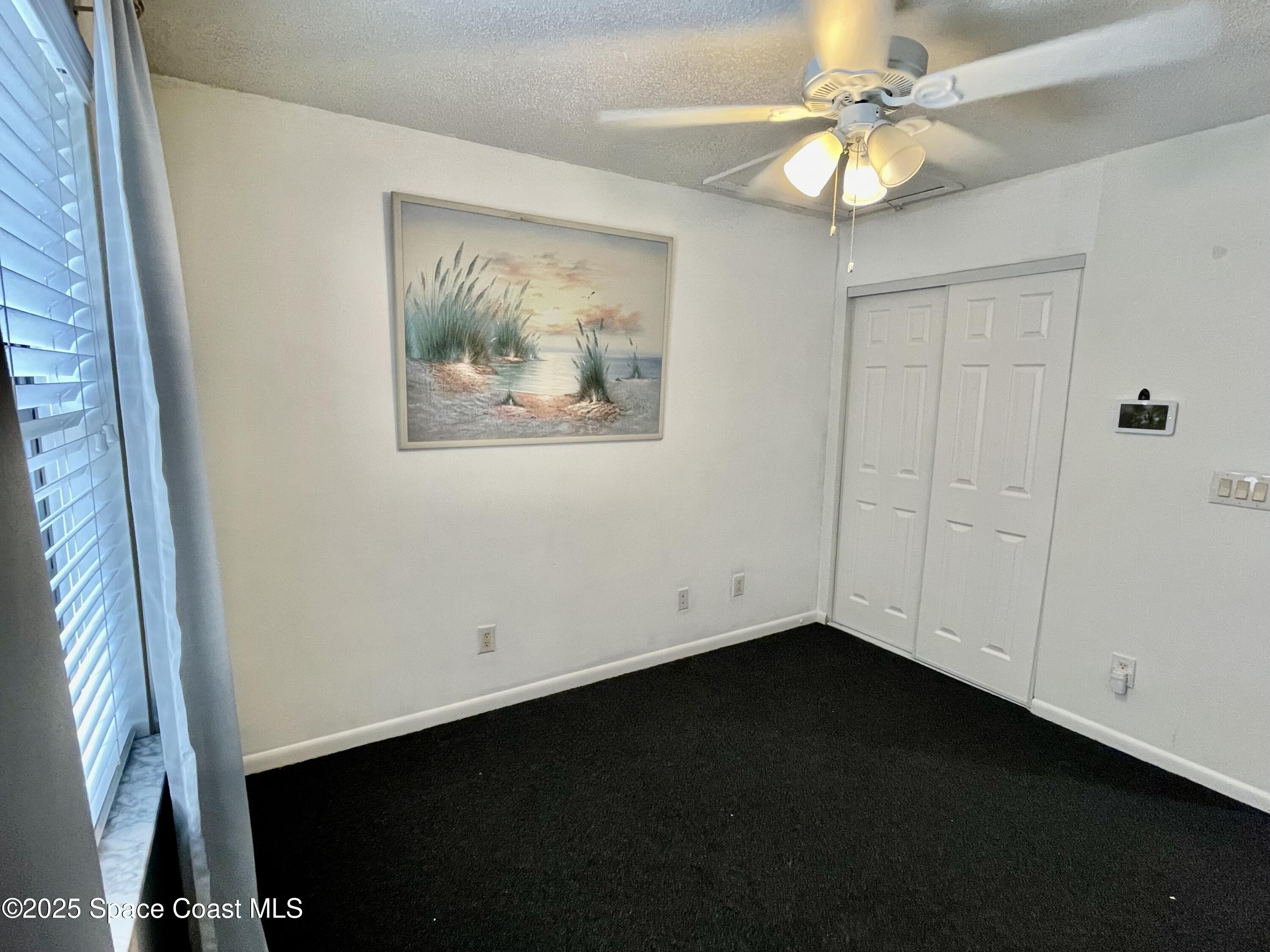 594 North Wickham Road, Unit 2 Melbourne, FL 32935 - Photo 22 of 42 an empty room with a ceiling fan and a window