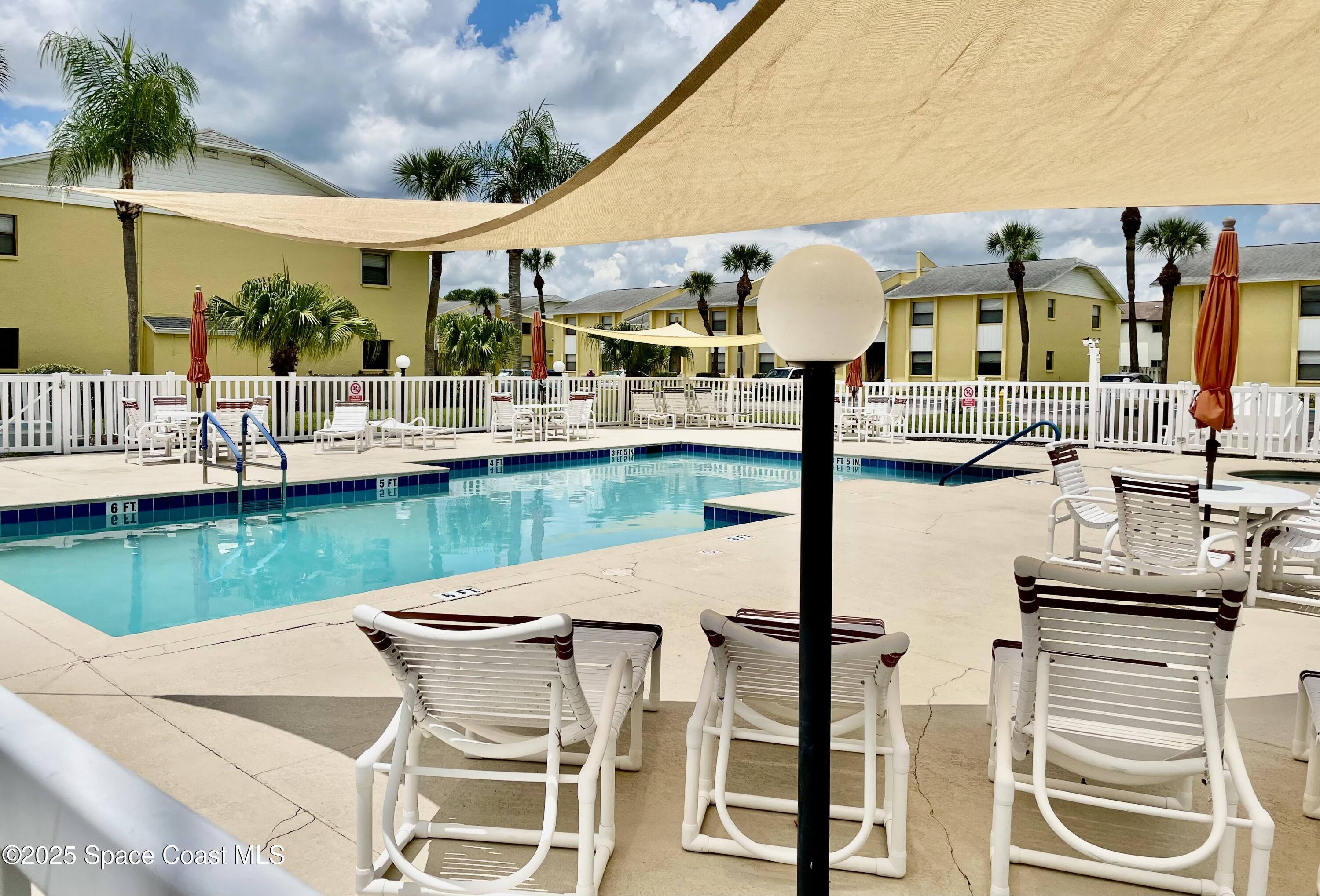 594 North Wickham Road, Unit 2 Melbourne, FL 32935 - Photo 38 of 42 a view of a patio with couches chairs table and chairs with wooden floor and fence