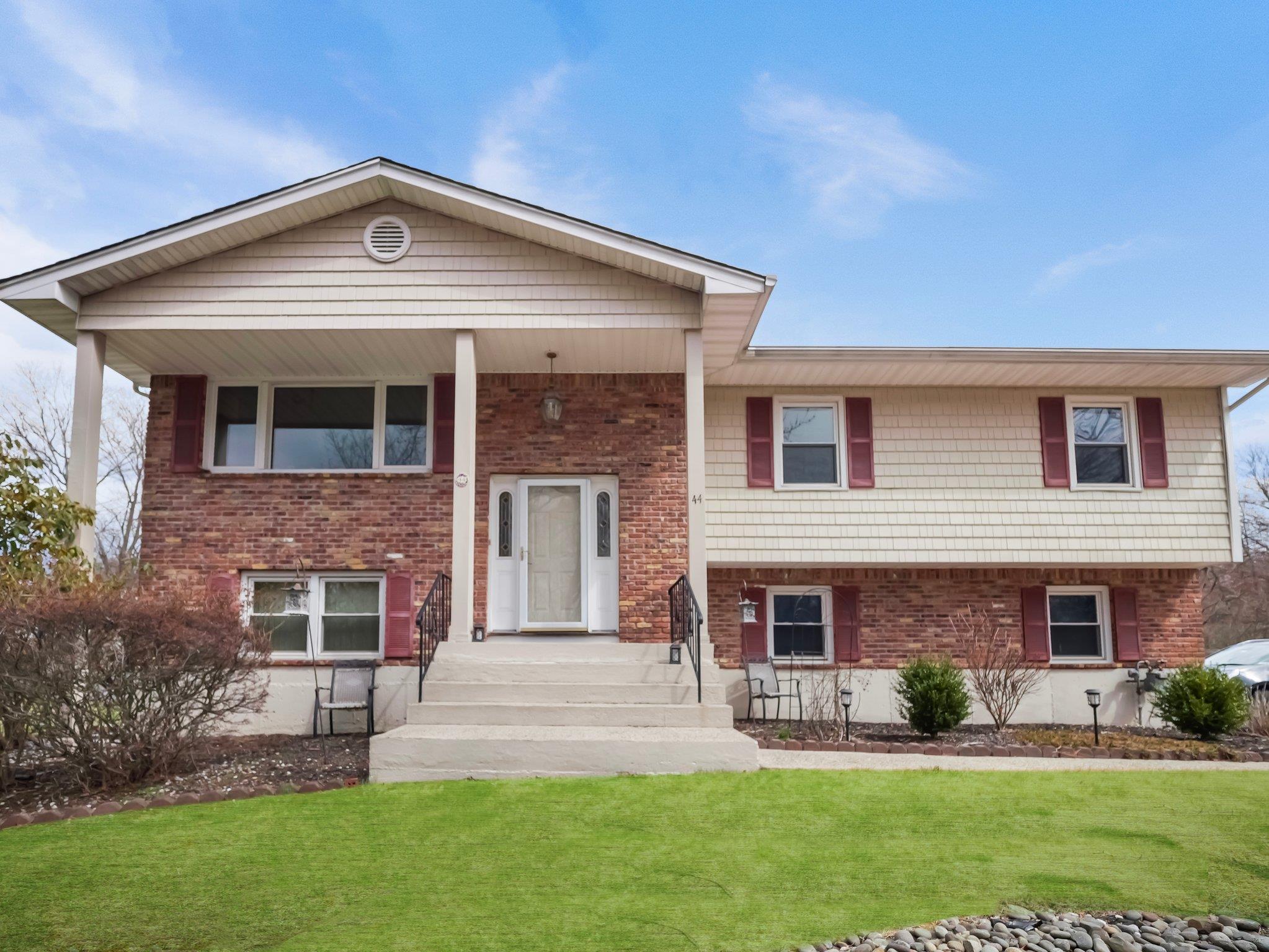 Raised ranch featuring brick siding and a front lawn