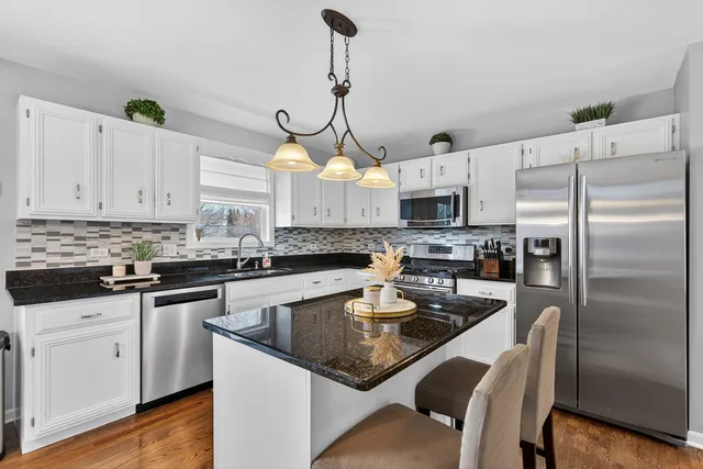 a kitchen with stainless steel appliances granite countertop a sink a stove a refrigerator and island