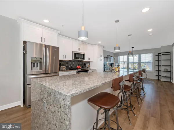 a kitchen with granite countertop a table chairs refrigerator and microwave