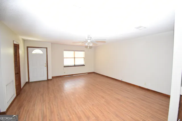 an empty room with wooden floor and windows