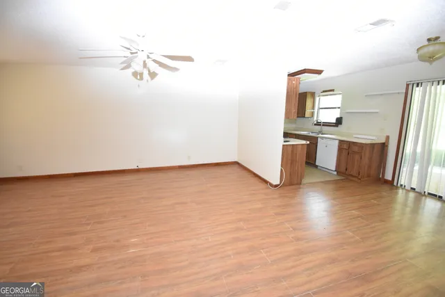 a view of empty room with wooden floor and fan
