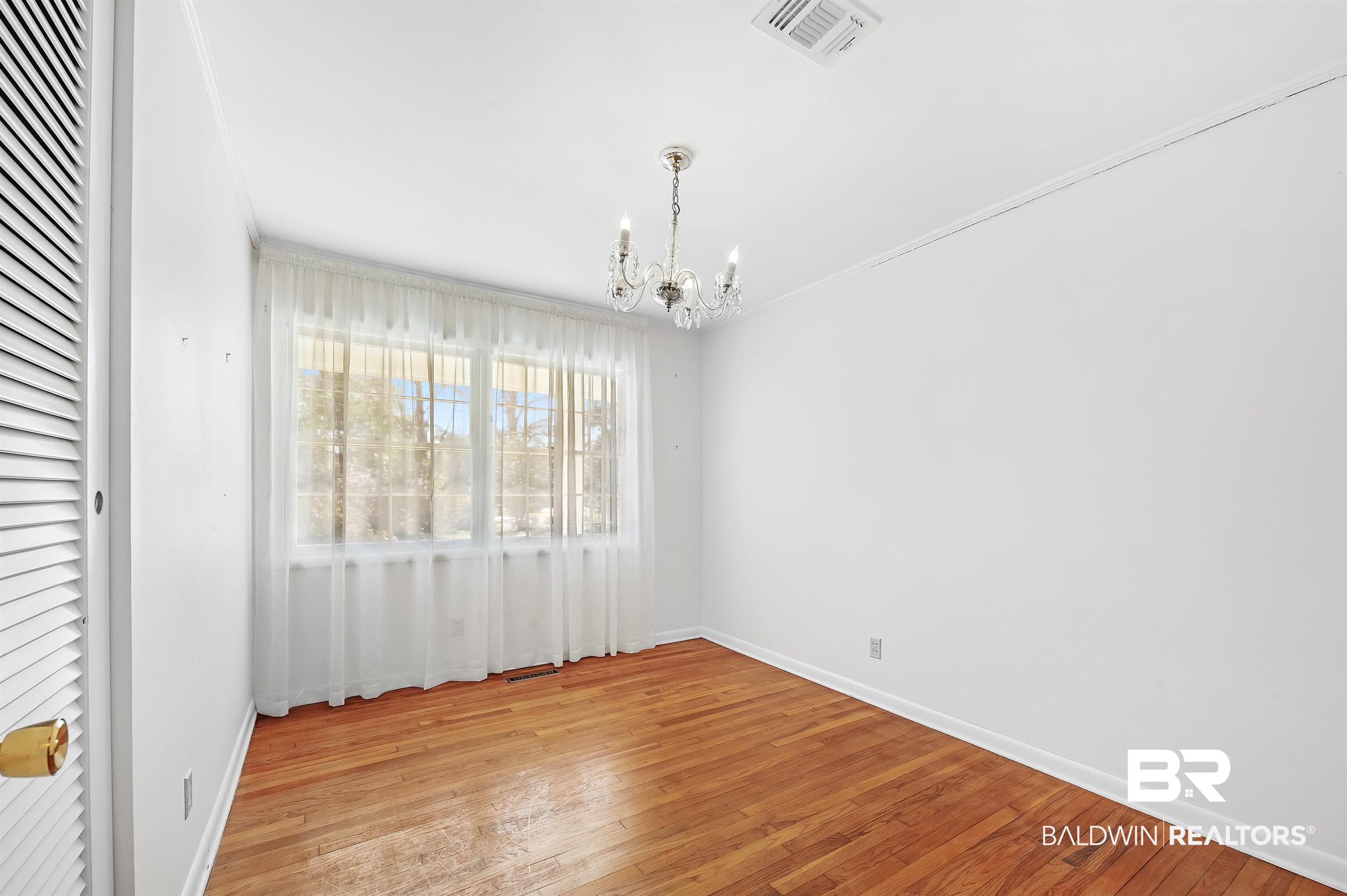 14375 Oak Street Magnolia Springs, AL 36555 - Photo 19 of 20 Third bedroom featuring oak hardwood floor and a notable chandelier