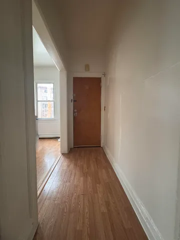 a view of hallway with window and wooden floor