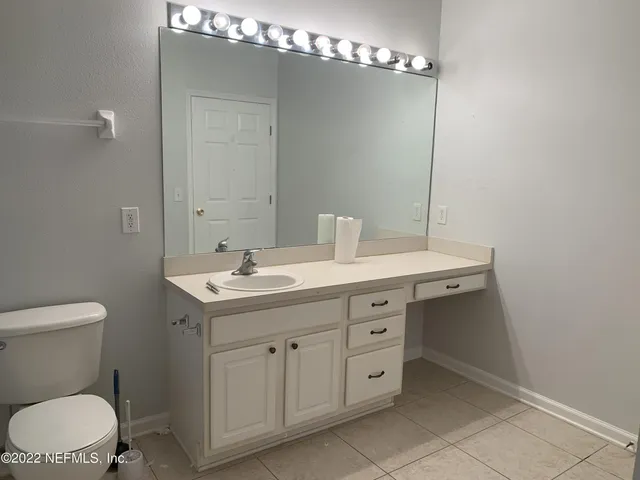 a bathroom with a toilet a sink a mirror and vanity