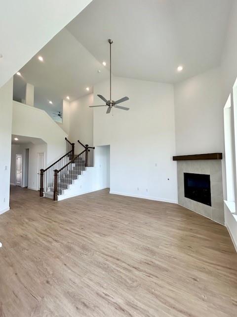 2204 Greenbelt Road Celina, TX 75009 - Photo 7 of 9 Spacious interior featuring soaring vaulted ceilings, recessed lighting, wood-finish flooring, a contemporary fireplace with a timber mantel, and a staircase with dark wood railings and balusters