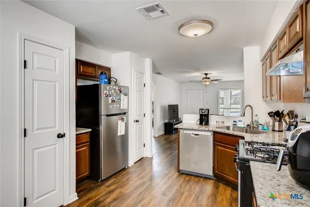 a kitchen with a refrigerator a sink and wooden floors