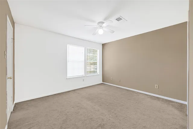 an empty room with windows and fan