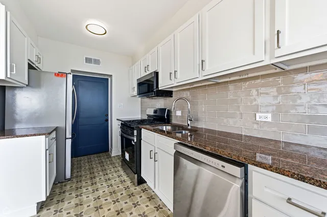 a kitchen with stainless steel appliances granite countertop a sink stove refrigerator and cabinets