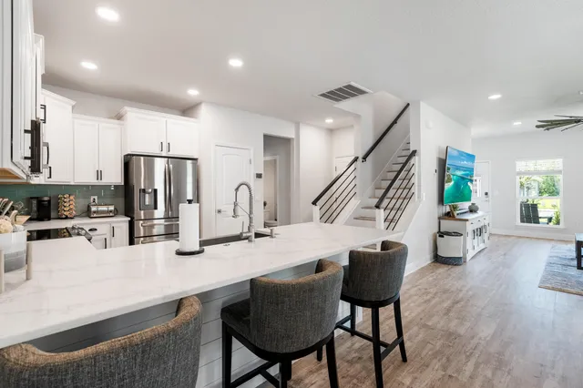 a kitchen with stainless steel appliances kitchen island granite countertop a refrigerator a stove a microwave oven a dining table and chairs with wooden floor