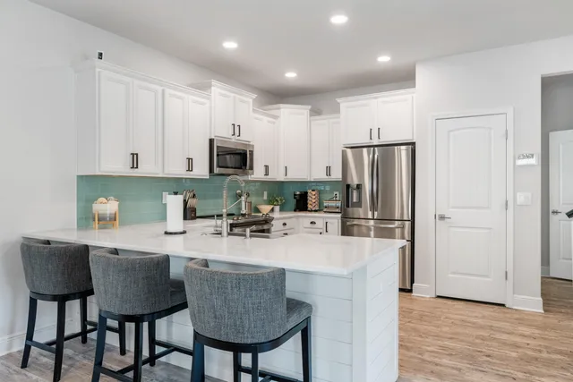 a kitchen with refrigerator a stove and chairs