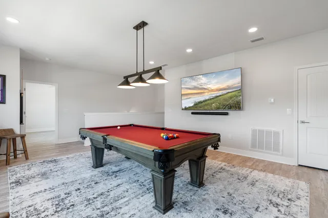 a room with pool table windows and wooden floor