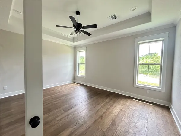 an empty room with wooden floor fan and windows