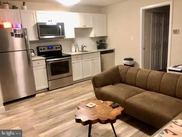 a living room with stainless steel appliances kitchen island granite countertop furniture and a wooden floor