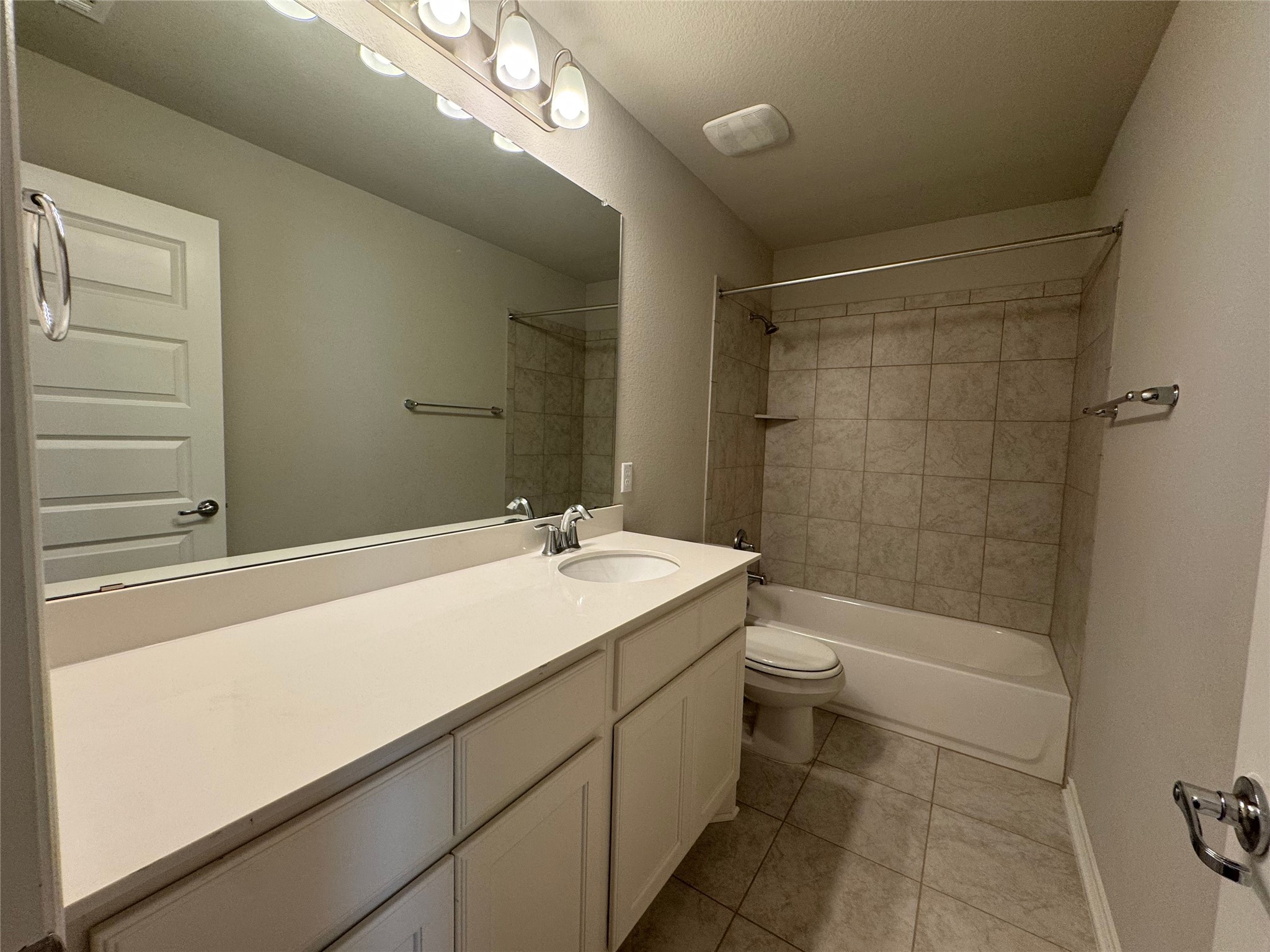 14100 McCoy Loop, Unit 1 Austin, TX 78717 - Photo 14 of 39 A well-lit bathroom features a spacious vanity with an integrated sink, a large mirror, and a tiled shower-tub combination.