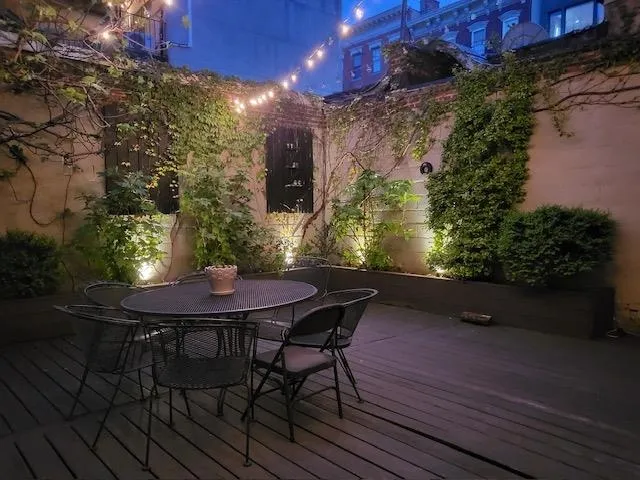 a backyard of a house with table and chairs with wooden floor