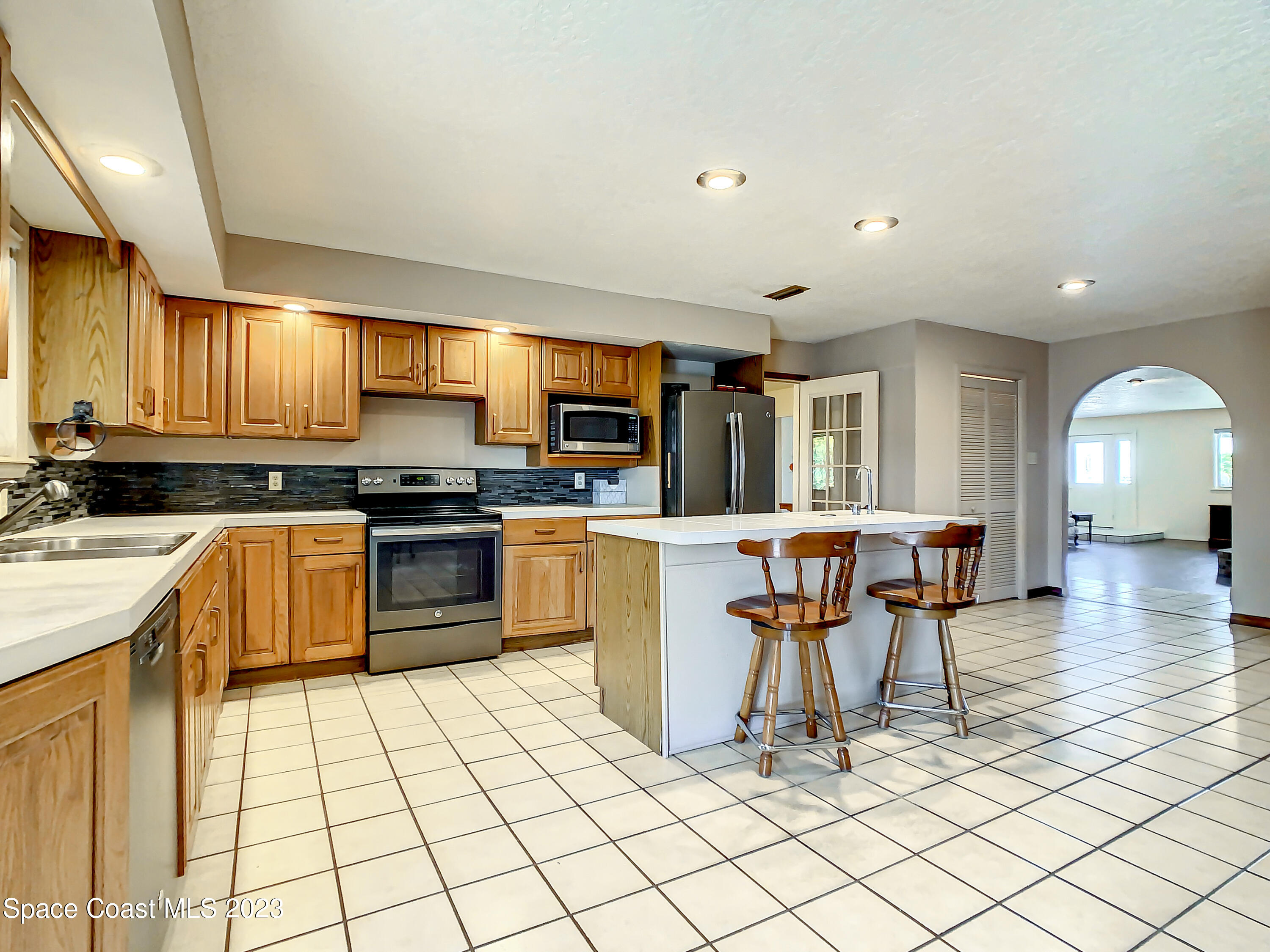 1675 East Riviera Drive Merritt Island, FL 32952 - Photo 17 of 50 a kitchen with stainless steel appliances kitchen island granite countertop a stove a sink a dining table and chairs
