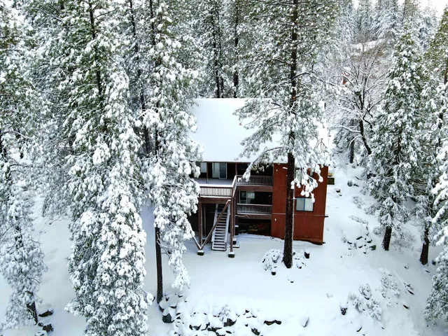 a kitchen with stainless steel appliances granite countertop a refrigerator a sink dishwasher a stove a dining table and chairs with wooden floor