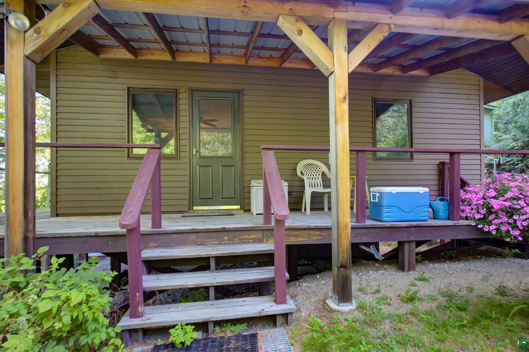 2811 Schaeffer Road Ely, MN 55731 - Photo 25 of 40 Covered porch with wood steps and railing, featuring a screened entry door, and horizontal siding