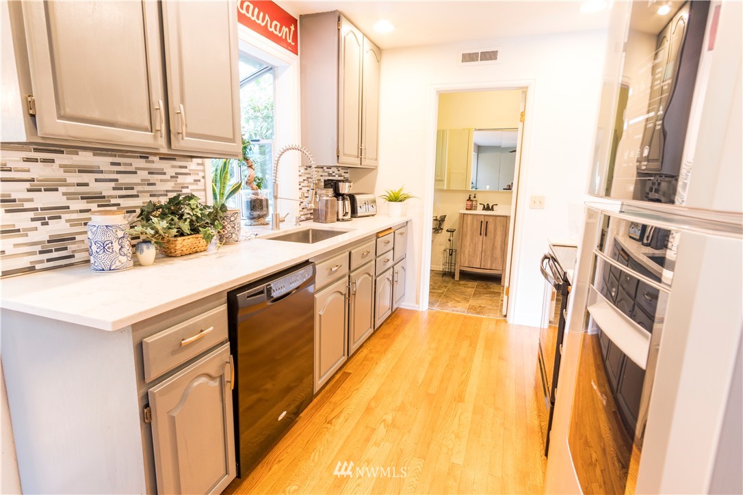 14634 Southeast 140th Street Renton, WA 98059 - Photo 8 of 35 a kitchen with a sink a stove cabinets and a wooden floor