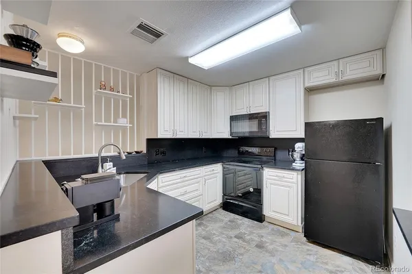 a kitchen with granite countertop a sink and a white cabinets