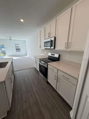 a kitchen with cabinets wooden floor and stainless steel appliances