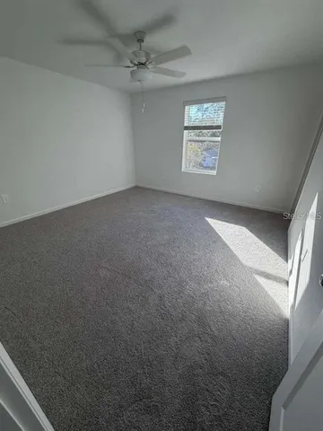 an empty room with windows and ceiling fan