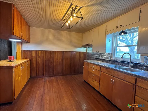 a kitchen with wooden floors cabinets and window