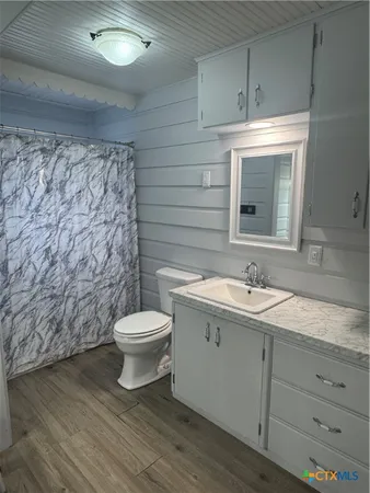 a bathroom with a granite countertop toilet a sink and mirror