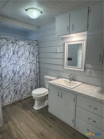 a bathroom with a granite countertop toilet a sink and mirror