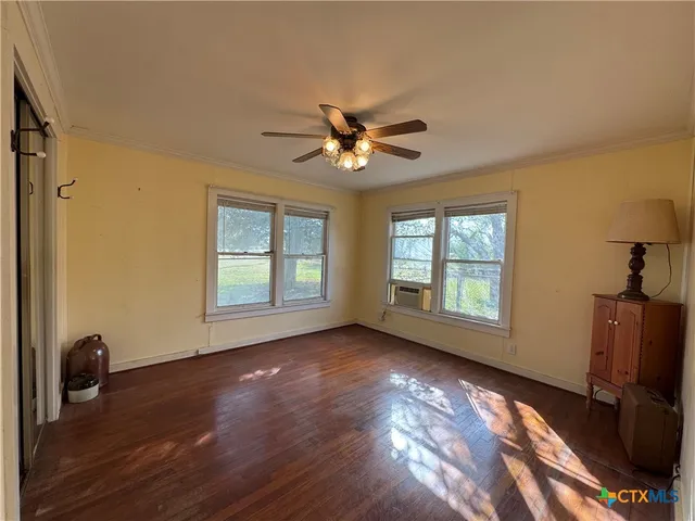 a view of empty room with wooden floor and fan