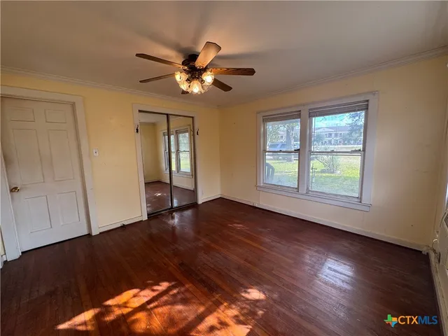 a view of an empty room with wooden floor and a window