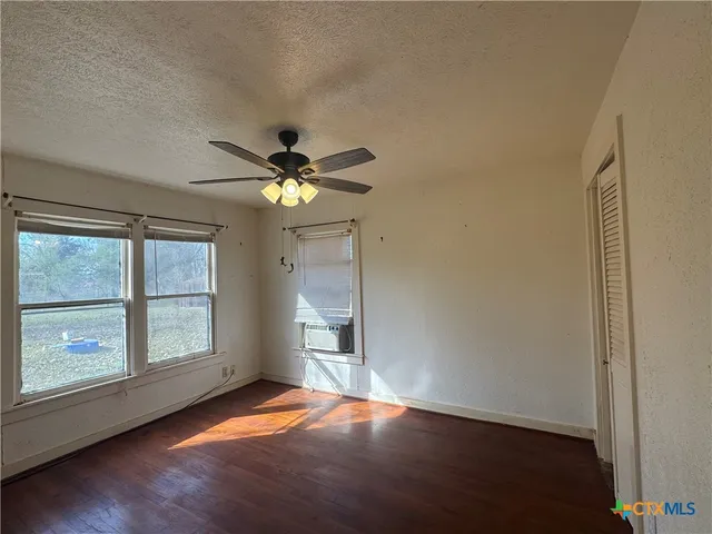 a view of empty room with wooden floor and fan