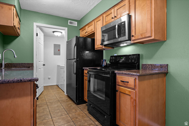 2095 South Main Street, Unit 13 Bountiful, UT 84010 - Photo 7 of 45 Kitchen with black appliances, dark stone countertops, a textured wall, a textured ceiling, and light tile patterned flooring
